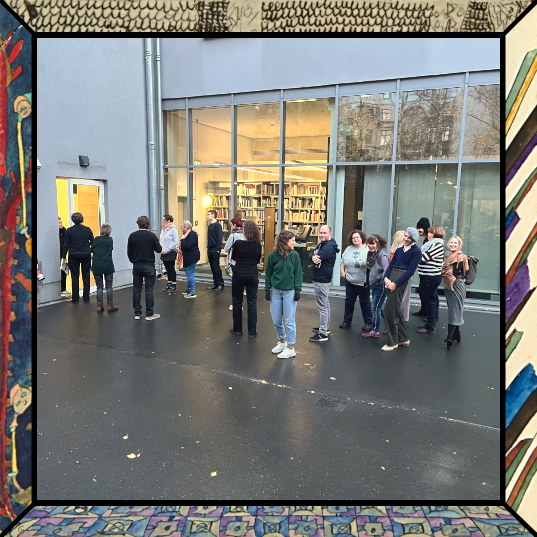 Eine Gruppe von Menschen steht vor dem Hintereingang der Berlinischen Galerie, der Boden ist Regennass