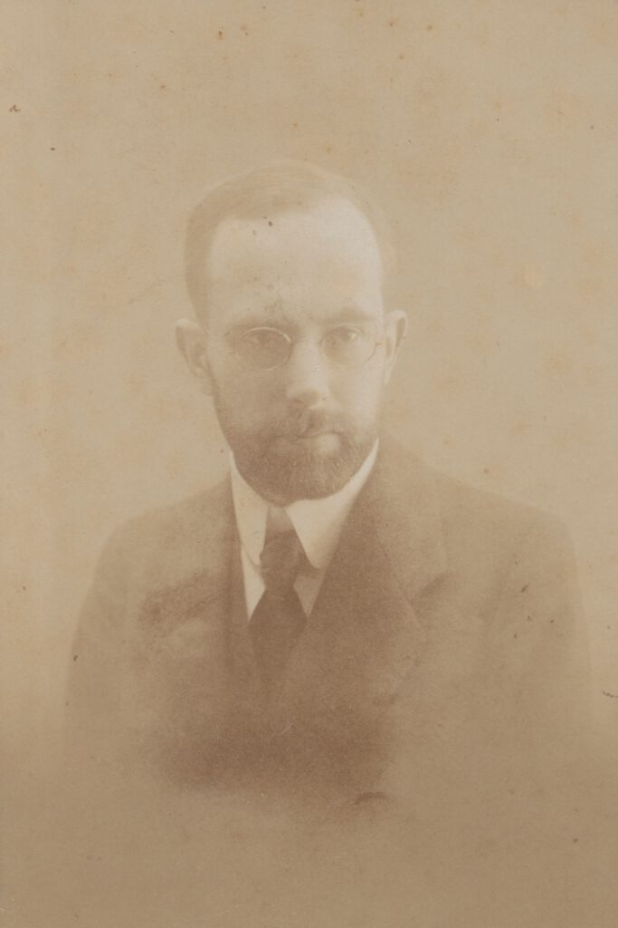 Portrait Paul Goesch. Ein altes Foto in Sepia Tönen. Ein Mann mit Brille und Bart. Er trägt einen Anzug und schaut ernst.
